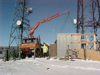 Unimog U1000 lifting an equipment cabin with a HIAB crane